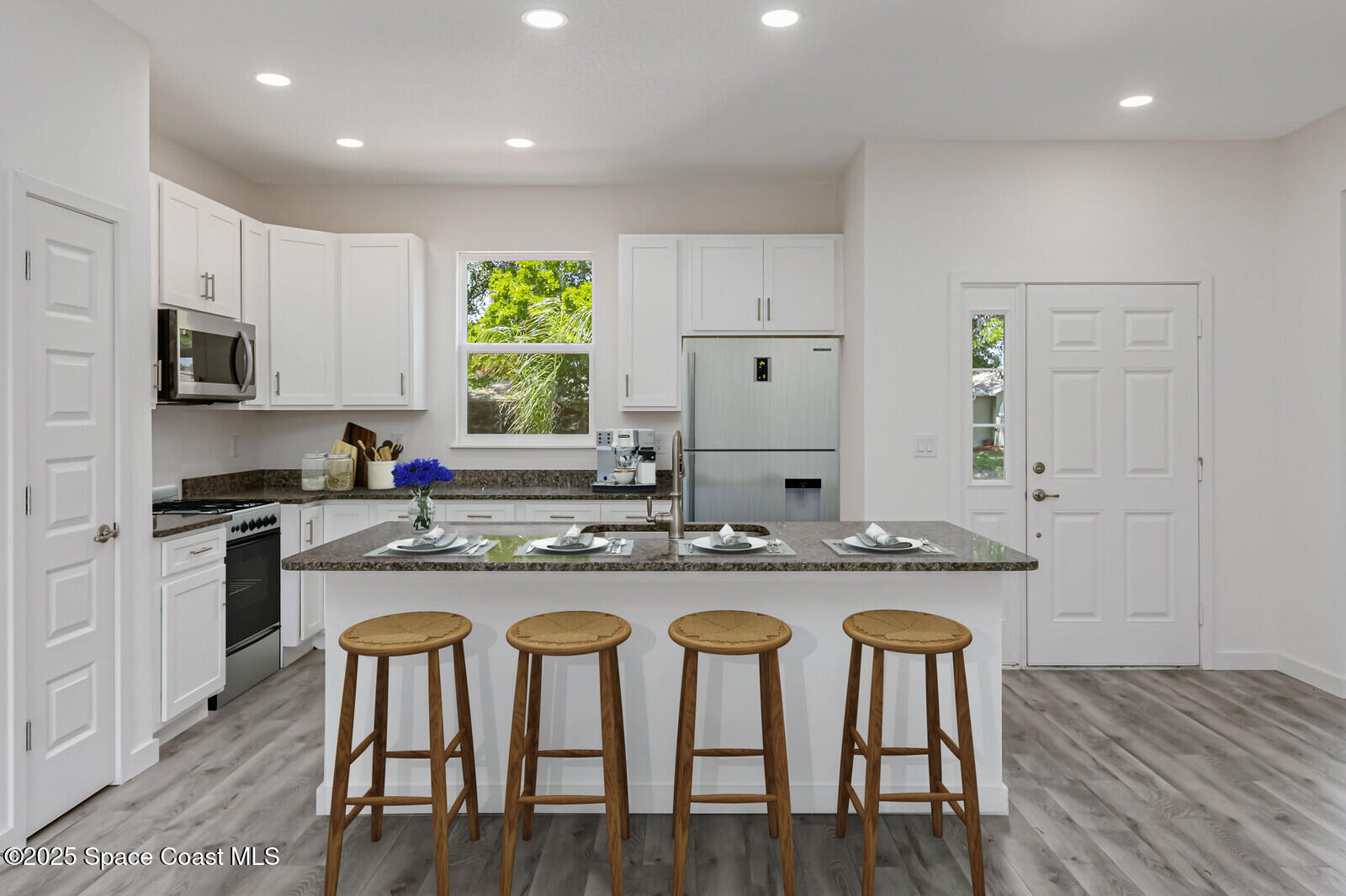 958 Chace Lane Northeast Palm Bay, FL 32905 - Photo 4 of 27 a kitchen with granite countertop wooden floor white cabinets and stainless steel appliances