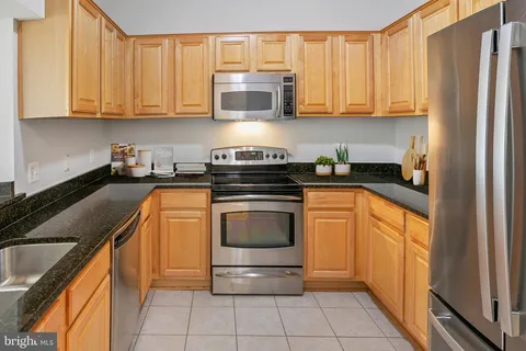 a kitchen with stainless steel appliances granite countertop a stove a sink and a refrigerator