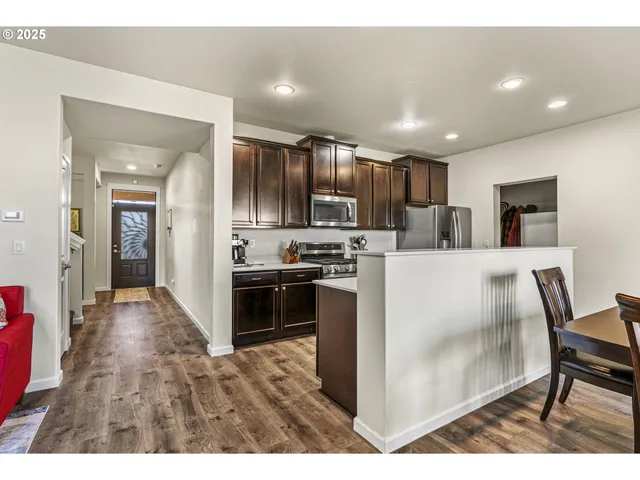 a kitchen with stainless steel appliances kitchen island granite countertop a refrigerator oven a sink a stove with island and chairs