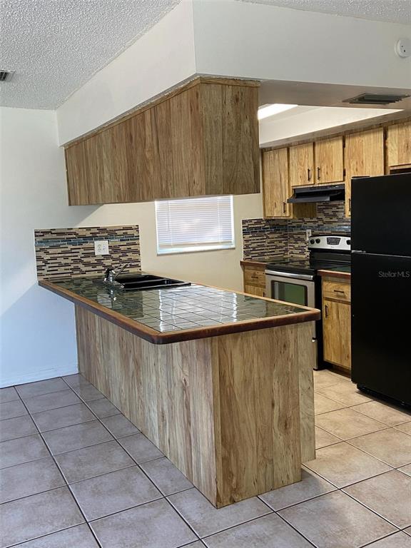 6429 Langston Avenue New Port Richey, FL 34653 - Photo 3 of 14 a kitchen with stainless steel appliances granite countertop a stove a sink and a microwave