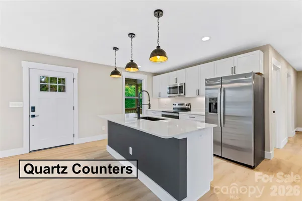 a kitchen with stainless steel appliances a refrigerator a stove a dining table and chairs with wooden floor