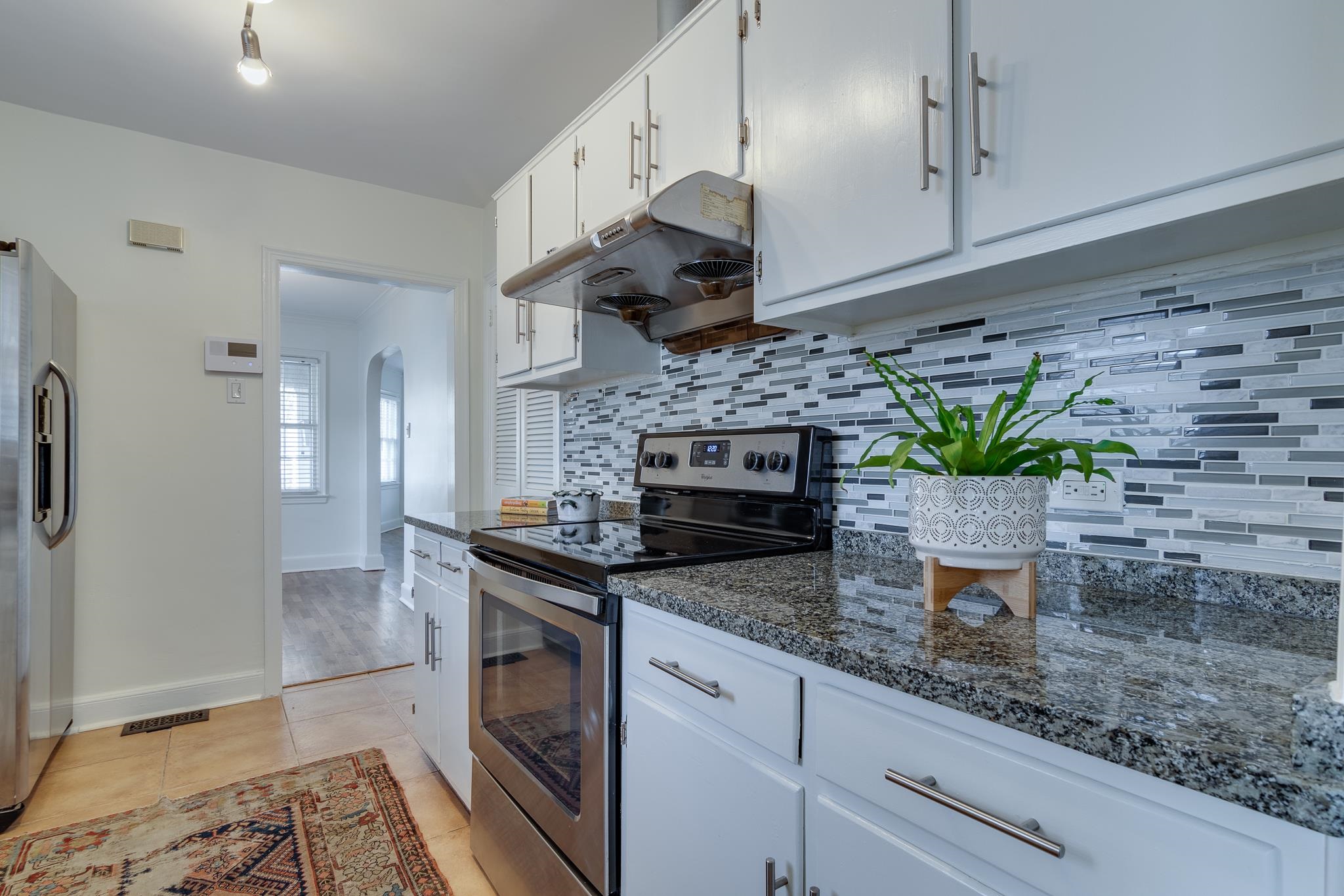 2767 Iroquois Road Memphis, TN 38111 - Photo 14 of 28 Kitchen with appliances with stainless steel finishes, light hardwood / wood-style flooring, decorative backsplash, white cabinetry, and dark stone countertops