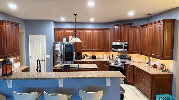 a kitchen with kitchen island granite countertop a sink appliances and cabinets