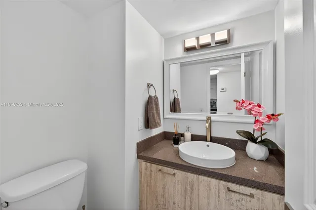 a bathroom with a granite countertop sink and a mirror with toilet
