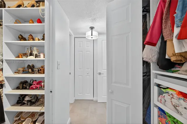 a view of walk in closet with clothes and shoes