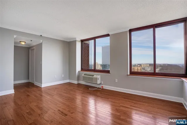 a view of an empty room with wooden floor and a window