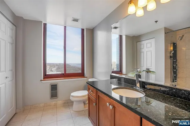 a bathroom with a granite countertop double vanity sink a mirror and a bathtub