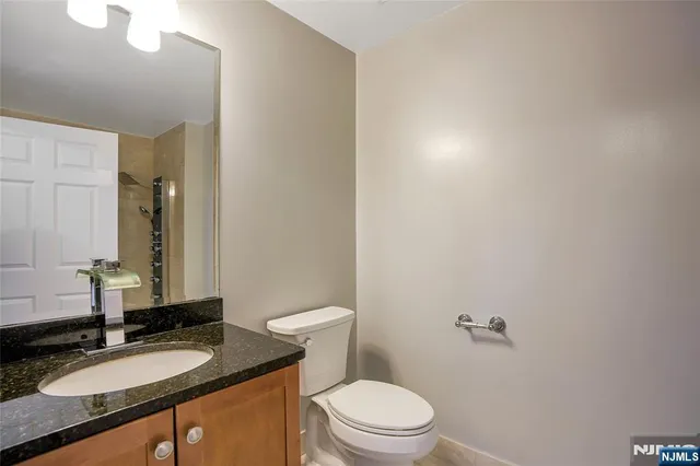 a bathroom with a granite countertop sink a toilet and a mirror