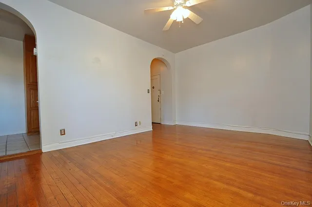 an empty room with wooden floor closet and chandelier