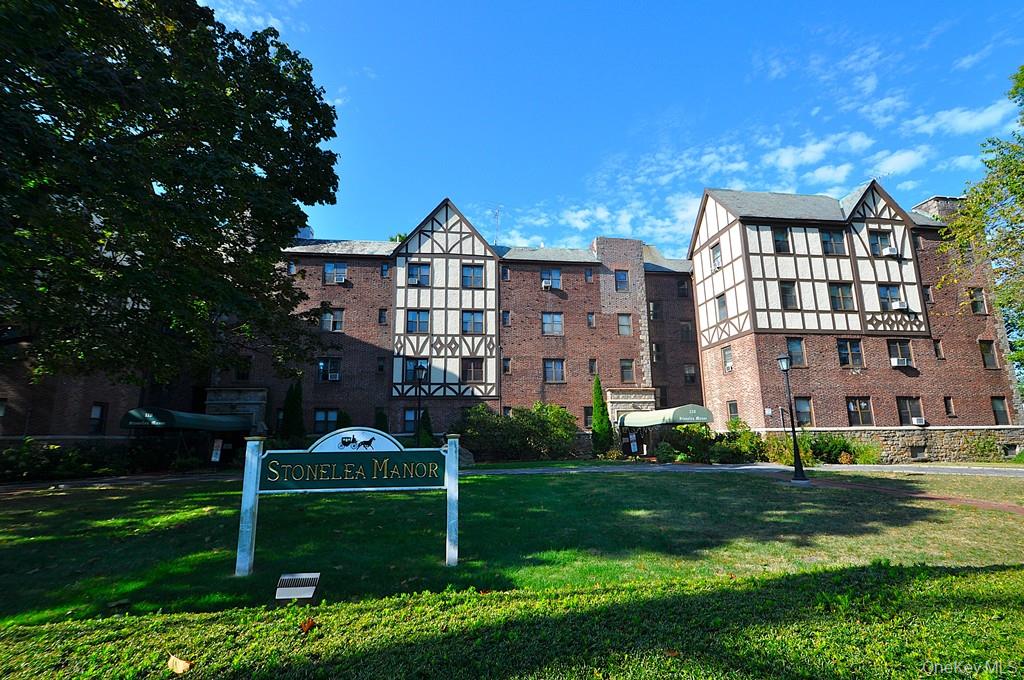 120 Stonelea Place, Unit 3M New Rochelle, NY 10801 - Photo 27 of 39 a view of a big yard in front of a brick house with a large tree