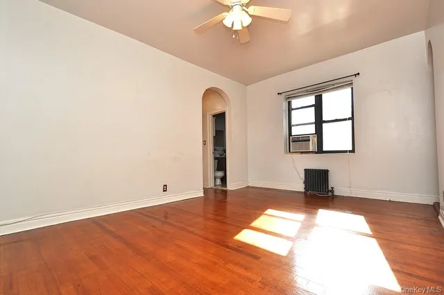 a view of an empty room with window and wooden floor