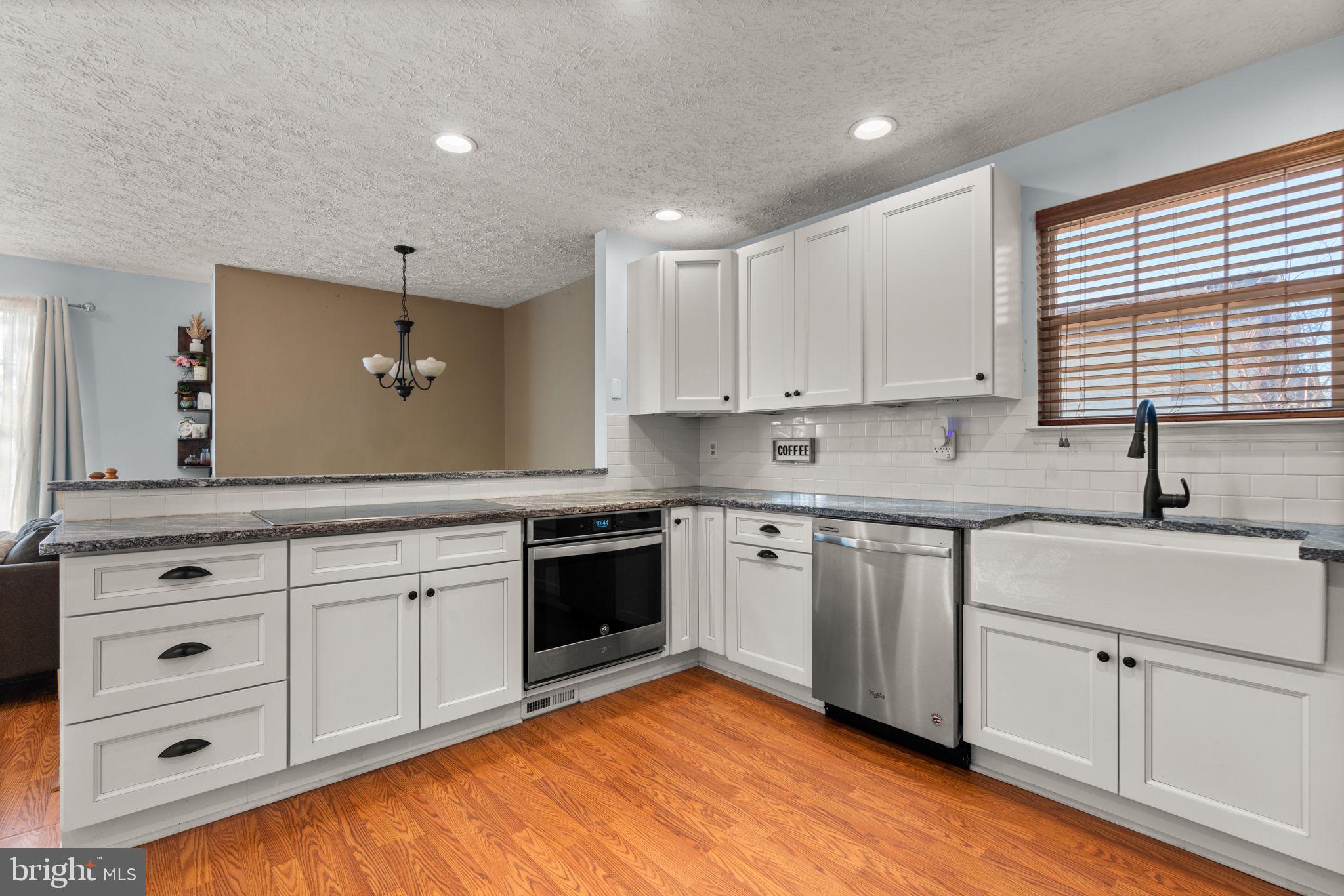 802 203rd Street Pasadena, MD 21122 - Photo 11 of 37 a kitchen with granite countertop white cabinets sink and stainless steel appliances