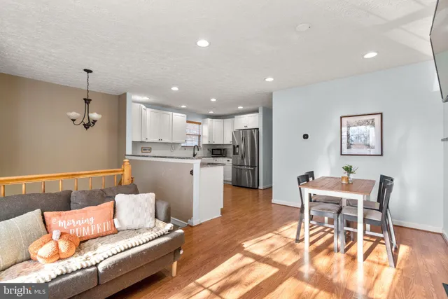 a living room with a couch and kitchen view with wooden floor