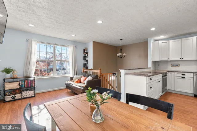a kitchen with a table chairs wooden floors and a view of living room