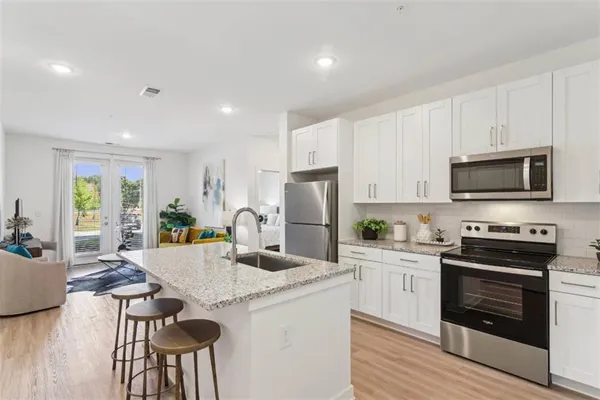a kitchen with stainless steel appliances kitchen island granite countertop a stove top oven a sink dishwasher and a refrigerator with wooden floor