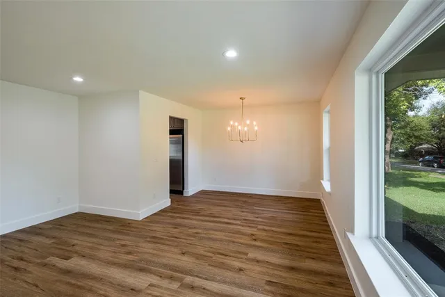 a view of a house next to a yard with plants and large trees