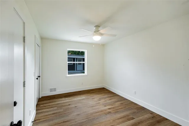 an empty room with wooden floor and fan