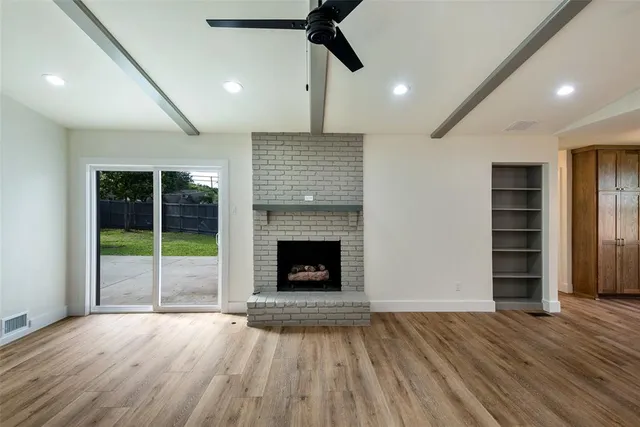 a view of an empty room with a fireplace and a window
