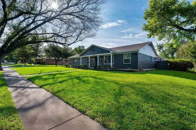 an empty room with wooden floor a ceiling fan a fireplace and windows