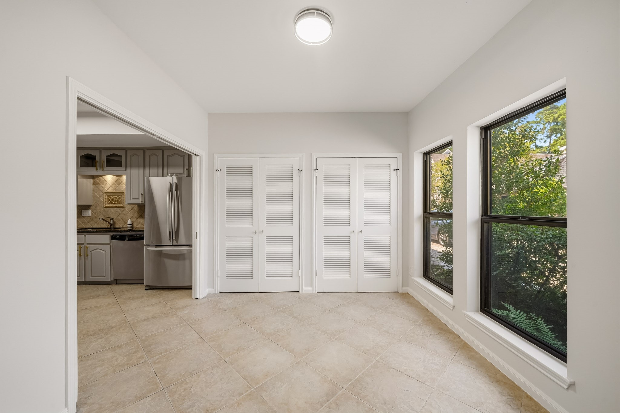 1746 South Gessner Road Houston, TX 77063 - Photo 4 of 25 Bright and inviting room featuring large windows, tiled flooring, and a view into a modern kitchen with stainless steel appliances.