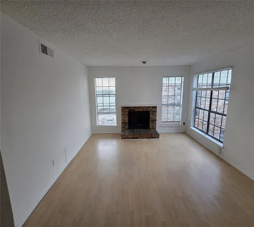 an empty room with windows and fireplace