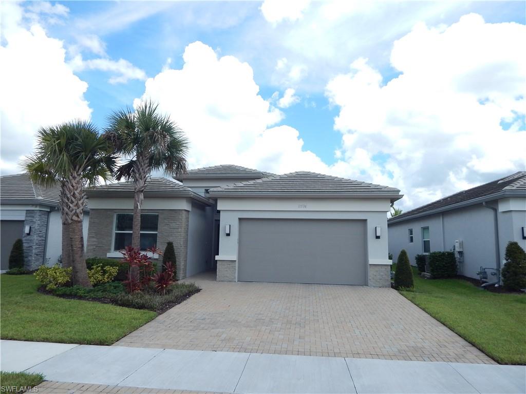 View of front of home with an attached garage, a front yard, decorative driveway, stucco siding, and a tile roof