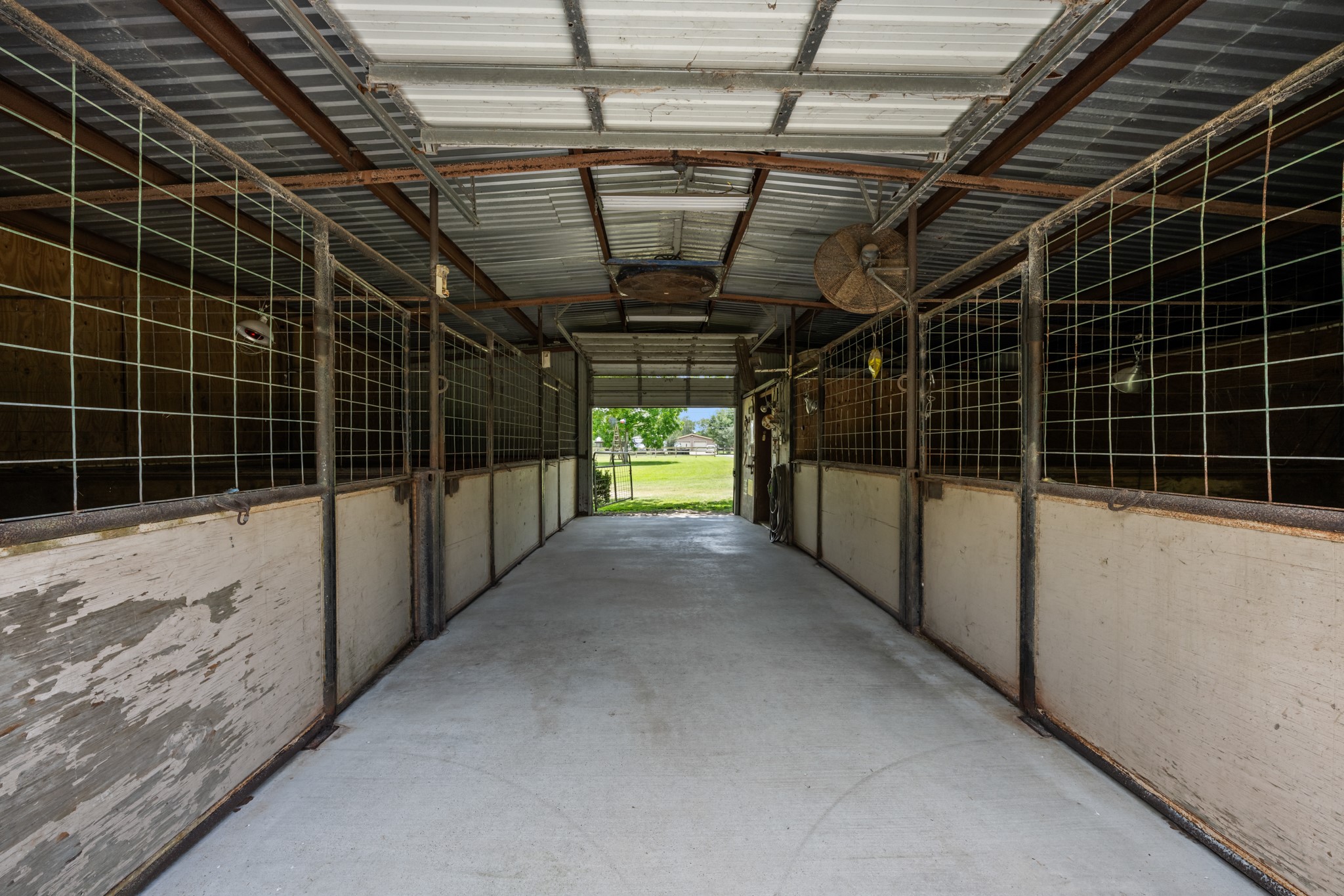 15602 Fir Road Santa Fe, TX 77517 - Photo 38 of 42 Spacious horse barn featuring multiple enclosed stalls, durable concrete flooring, overhead ventilation, and a wide center aisle for easy access and daily operation. Ideal setup for livestock care and equestrian use.