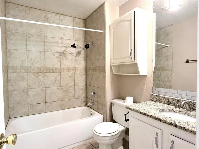 a bathroom with a granite countertop bathtub shower sink mirror vanity and toilet