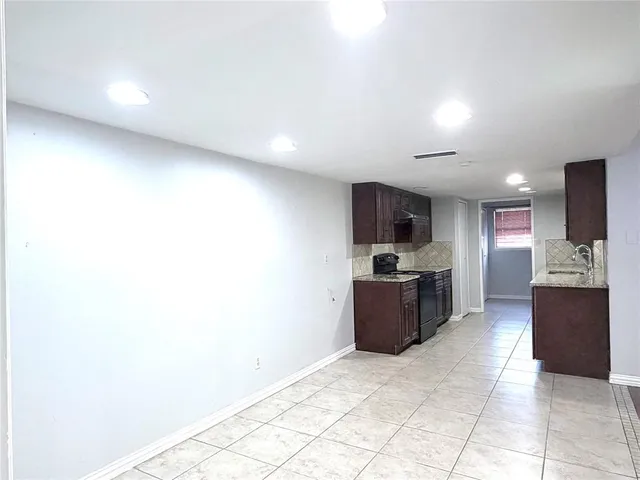 a large kitchen with a sink and a stove top oven with wooden floor