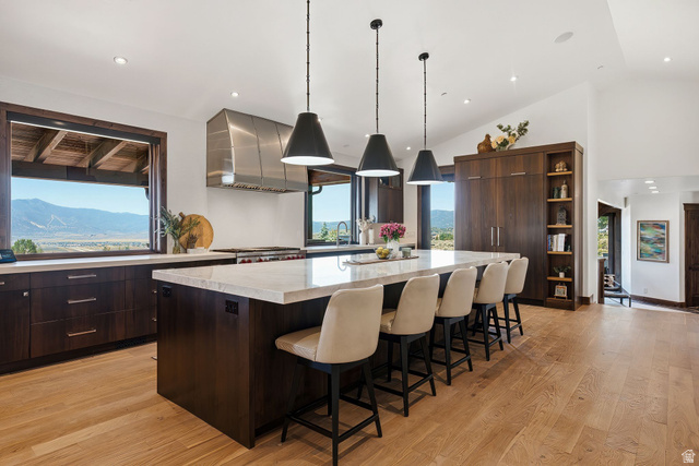7885 North Rabbitbrush Court, Unit 13 Park City, UT 84098 - Photo 11 of 88 Spacious kitchen featuring an expansive central island with seating, pendant lighting, wood-finish flooring, and dark wood cabinetry with integrated shelving