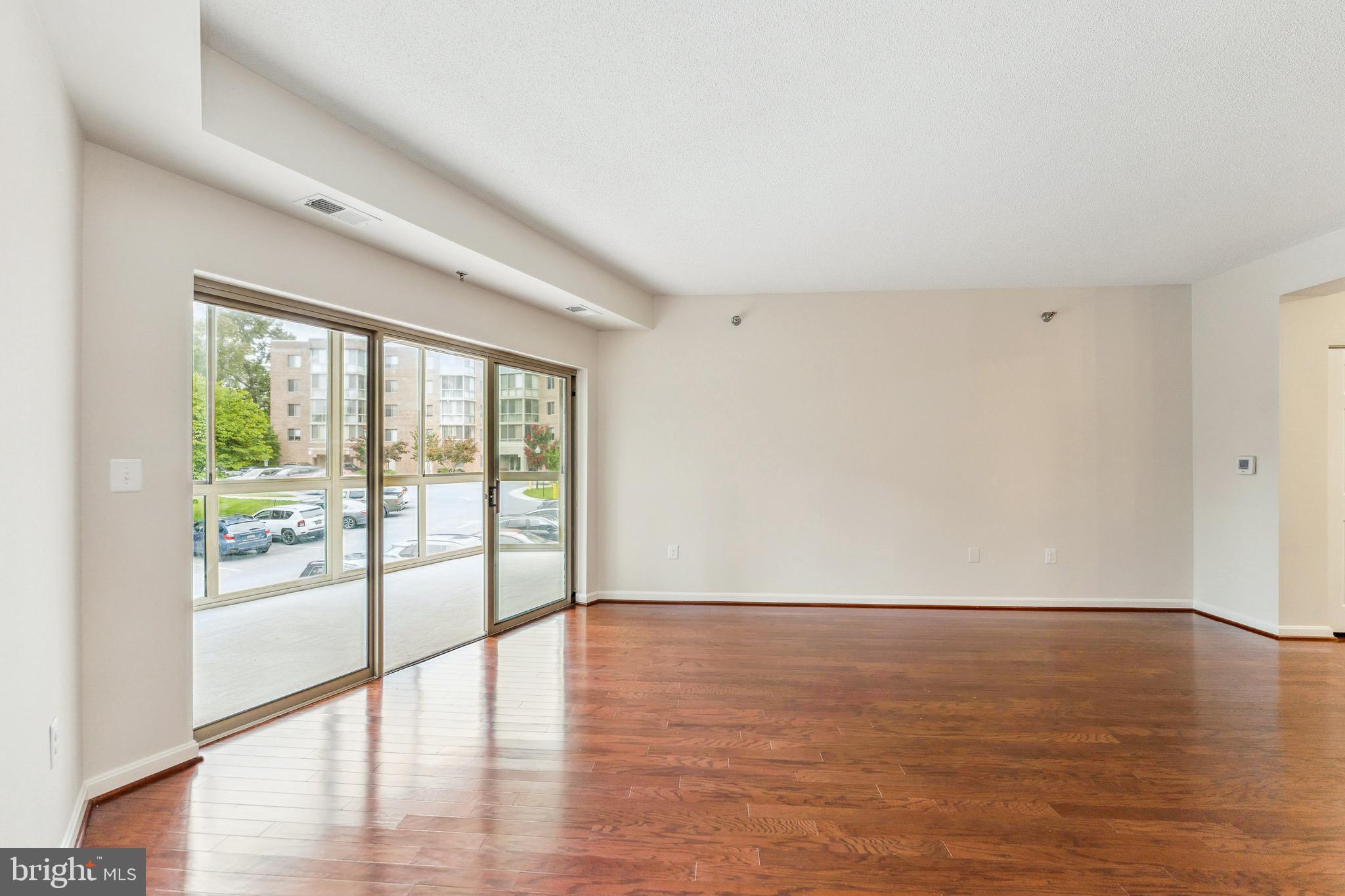 2900 North Leisure World Boulevard, Unit 209 Silver Spring, MD 20906 - Photo 7 of 24 a view of an empty room with wooden floor and a window