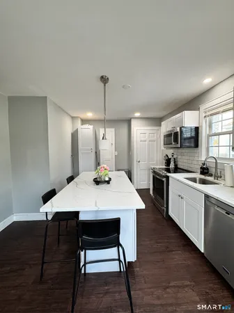 a large kitchen with a table chairs sink and wooden floor