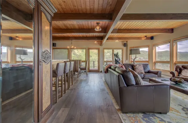 a living room with lots of wooden furniture and large windows