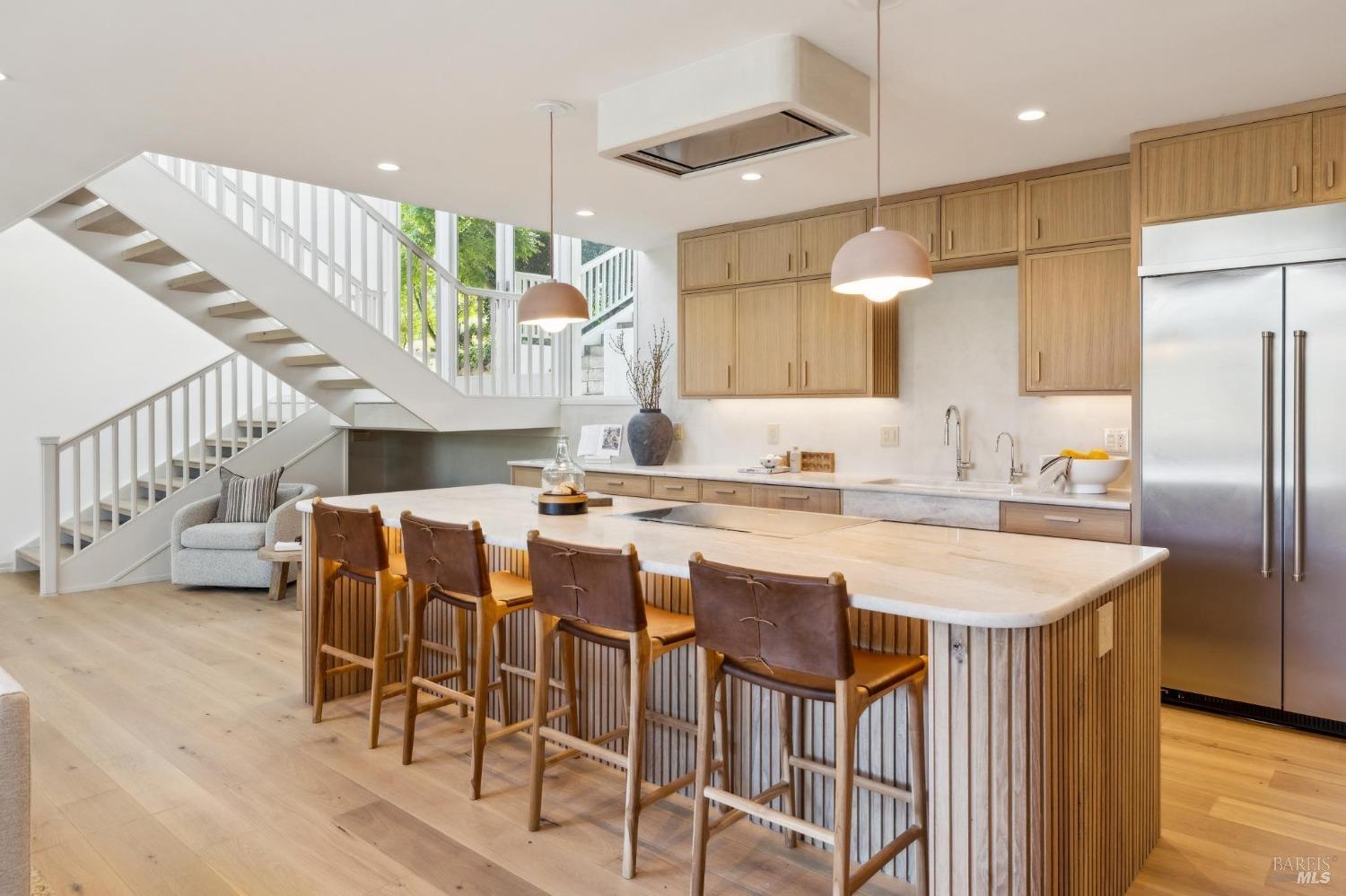 a kitchen with stainless steel appliances kitchen island granite countertop a table chairs and a refrigerator