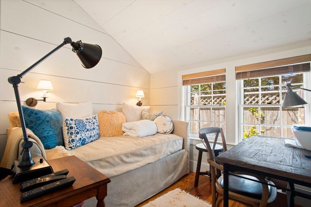 a large white bed in a bedroom next to a window