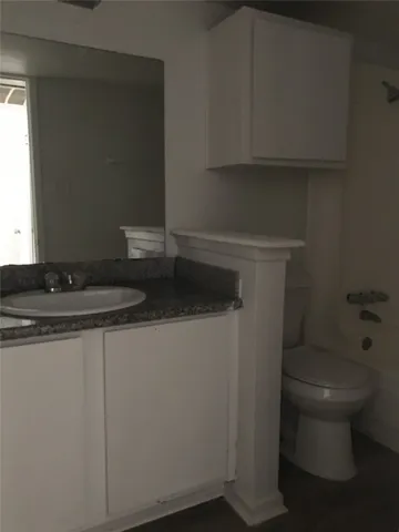 a bathroom with a granite countertop toilet and a sink