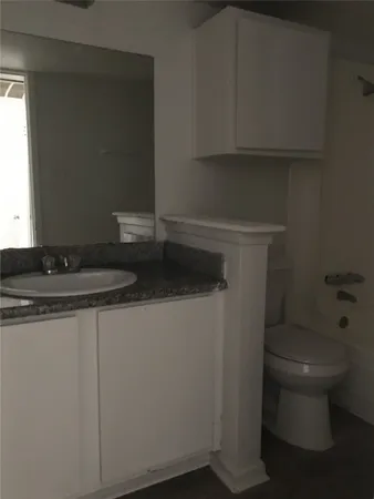 a bathroom with a granite countertop toilet and a sink