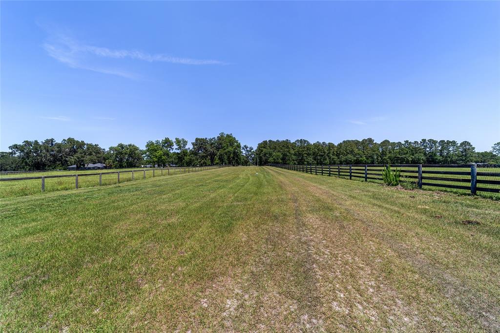 16490 Northwest 122nd Terrace Reddick, FL 32686 - Photo 12 of 24 a view of a field with wooden fence and trees in the background