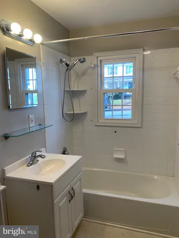 a bathroom with a sink vanity mirror and a bathtub