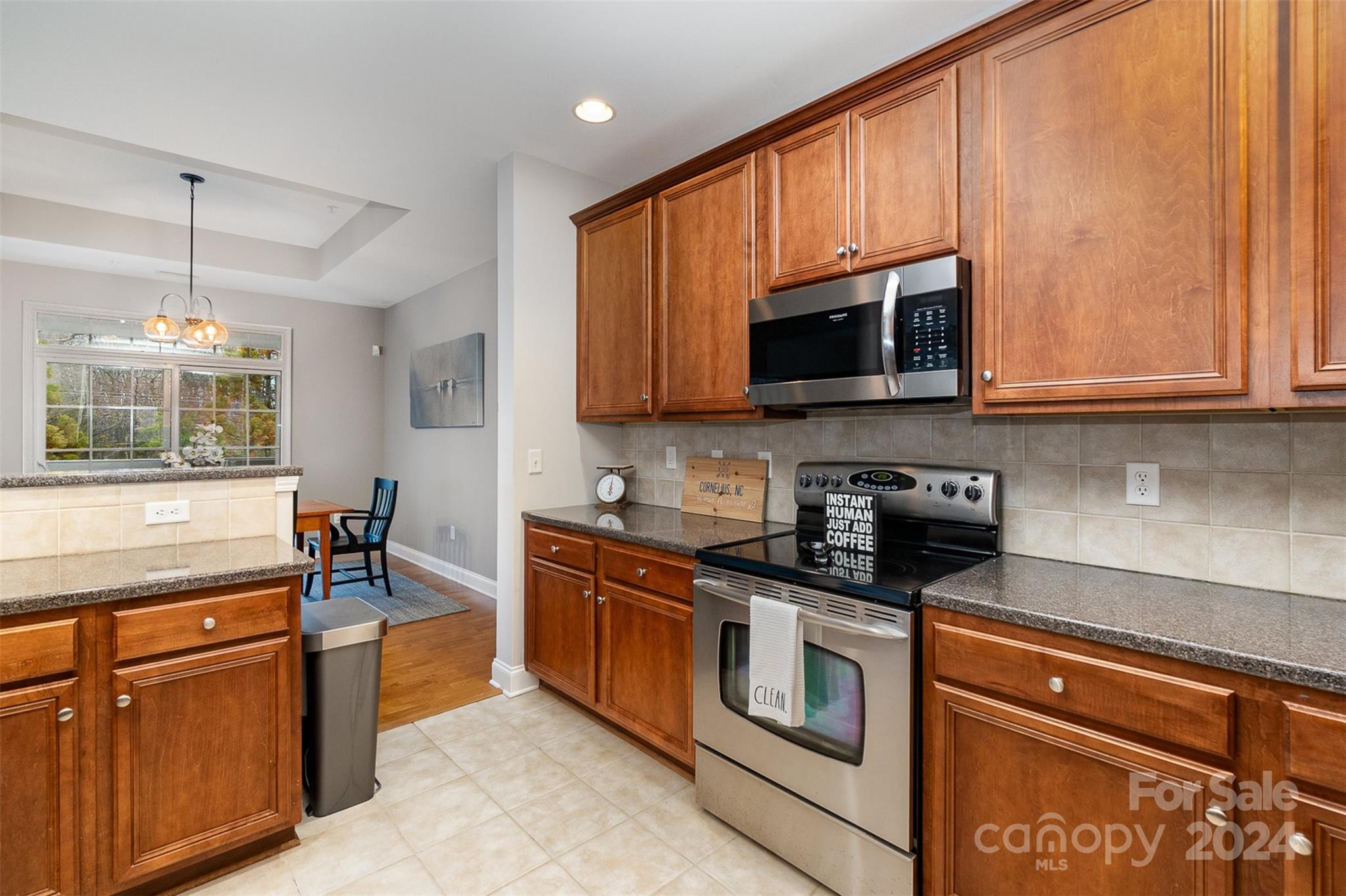 8653 Edinburgh Square Drive Cornelius, NC 28031 - Photo 4 of 22 a kitchen with stainless steel appliances granite countertop wooden cabinets a stove top oven a sink and dishwasher