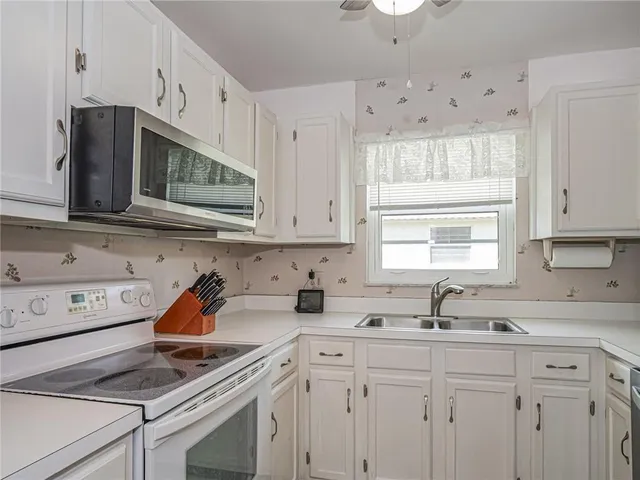 a kitchen with cabinets appliances a sink and a window