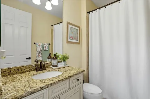 a bathroom with a granite countertop sink and a mirror with toilet