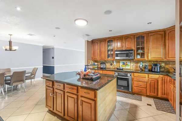 a kitchen with stainless steel appliances granite countertop a stove a sink dishwasher and a refrigerator with wooden cabinets