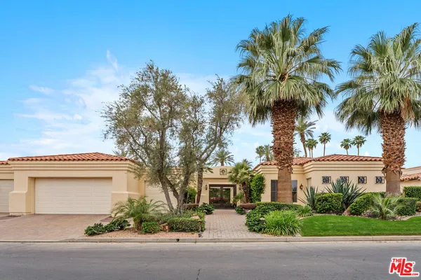 front view of a house with a yard and palm trees