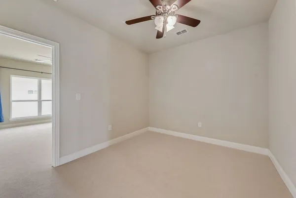 an empty room with a chandelier fan and windows