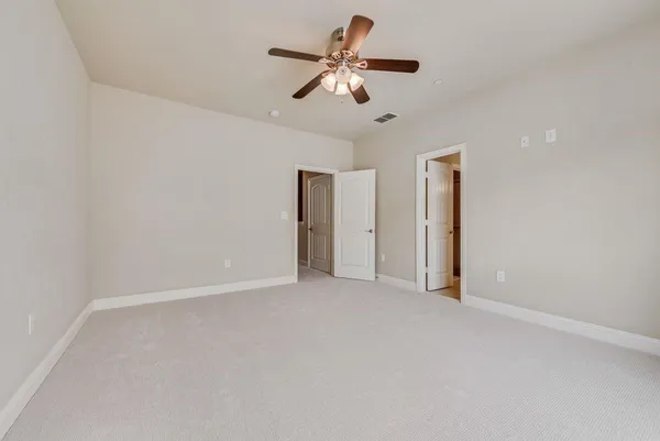 an empty room with closet and a ceiling fan