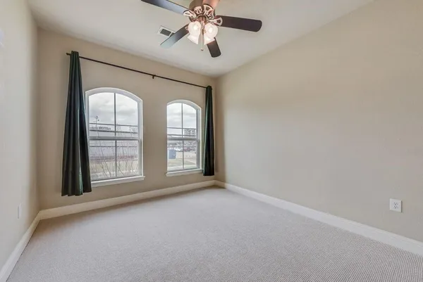 an empty room with chandelier fan and windows