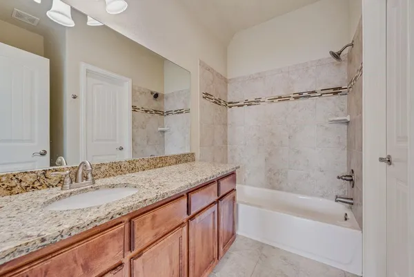 a bathroom with a granite countertop sink mirror toilet and bathtub