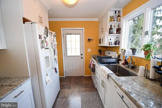 a kitchen with stainless steel appliances granite countertop a refrigerator a stove and a sink with wooden floor