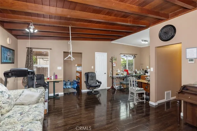a living room with couches and kitchen view with wooden floor